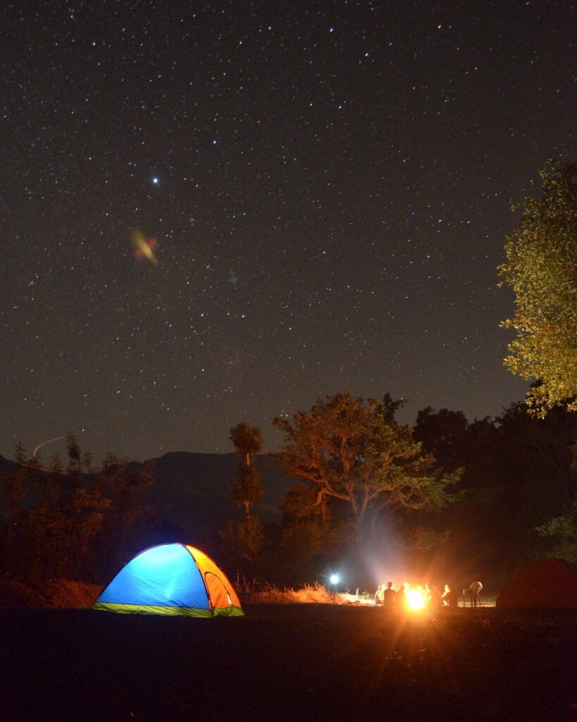 a tent and campers beneath a starry sky