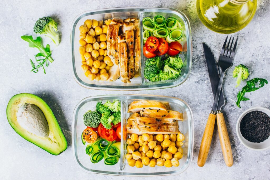 two glass containers with meal preps on a gray surface